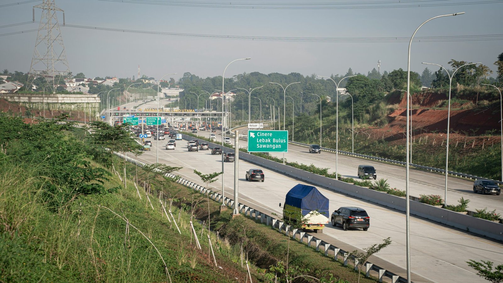 a highway filled with lots of traffic next to a lush green hillside